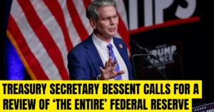 Treasury Secretary Scott Bessent speaking in front of a blue background with the Federal Reserve seal, alongside a bold headline that reads: "Treasury Secretary Bessent Calls for a Review of 'The Entire' Federal Reserve."